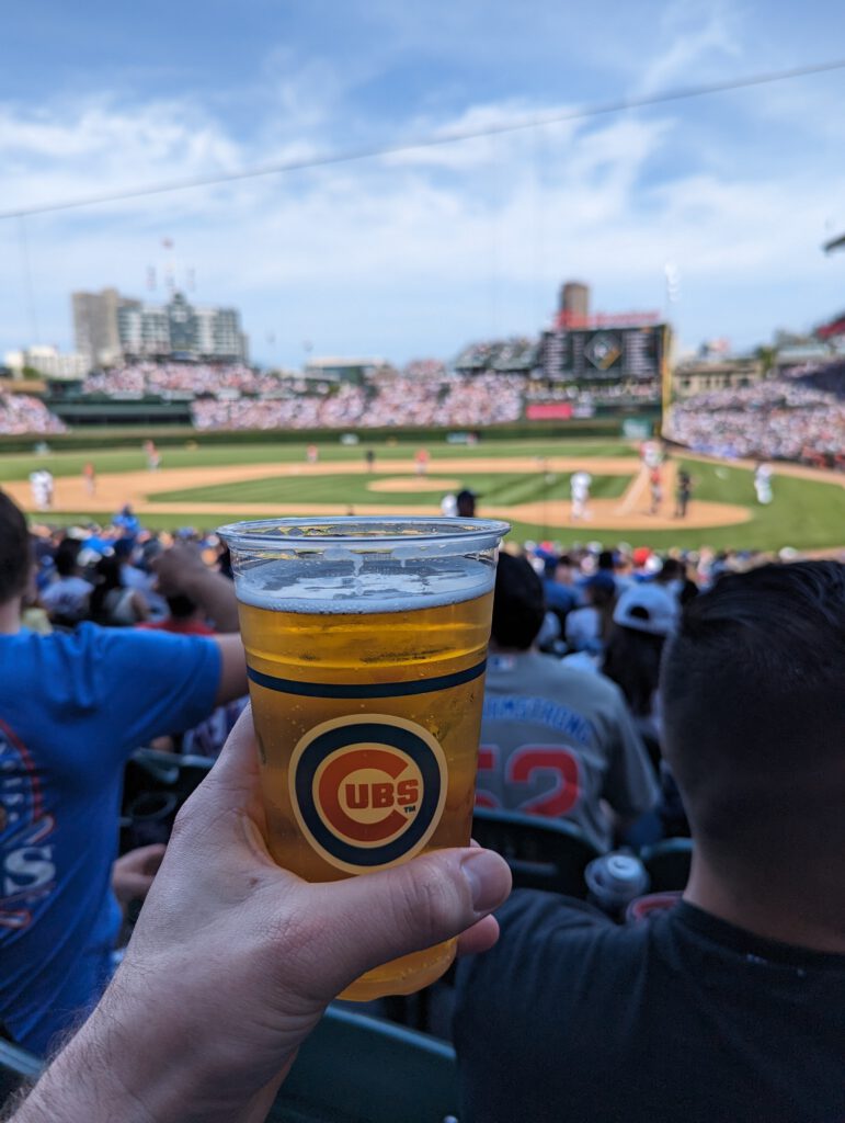 Me holding a plastic cup of Heileman's Old Style, with Wrigley Field Stadium in the background.