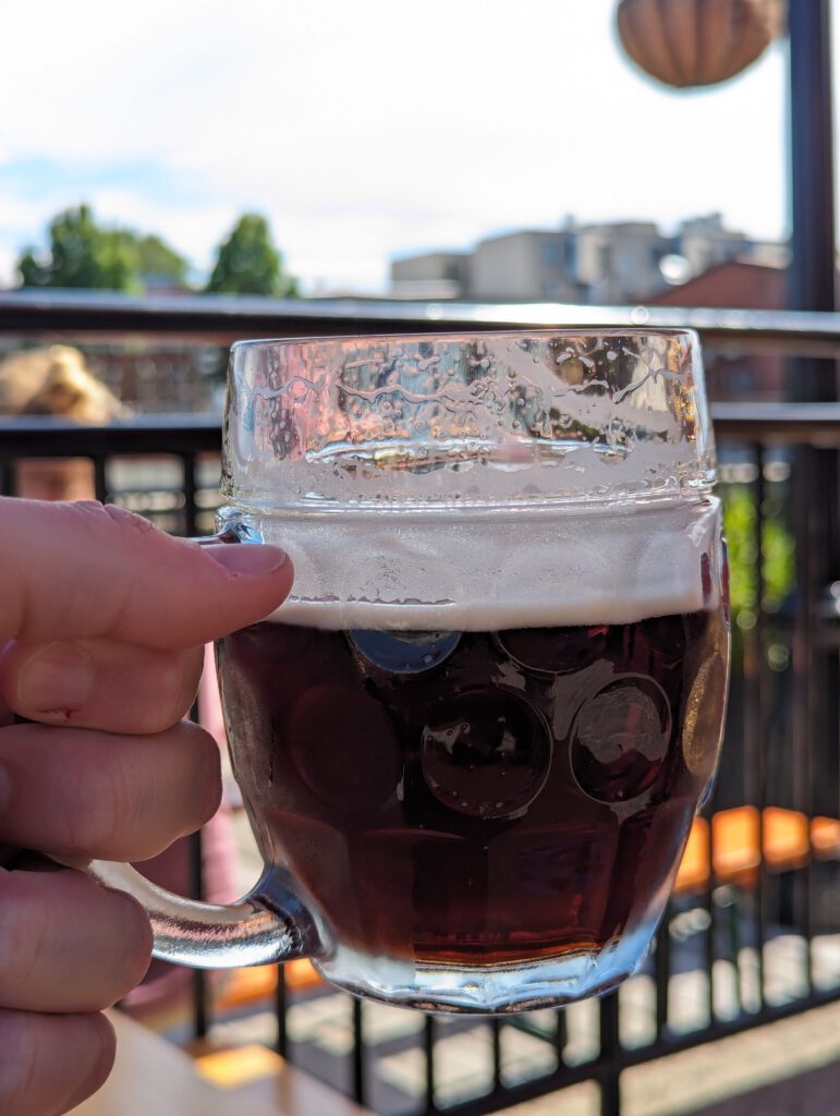 A Tübinger glass with Notch Tmavý. Thick foam sticks to the side of the glass, while the beer is a very dark brown that still lets pass through a little bit of light.