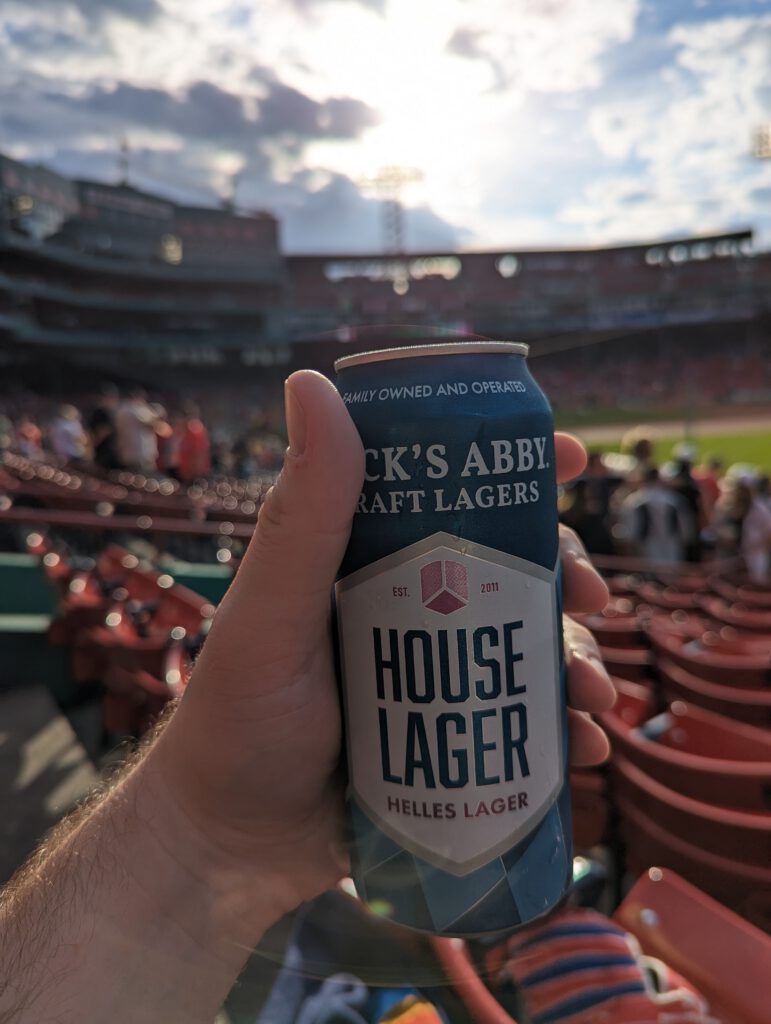 My hand holding up a can of Jack's Abby House Lager, with Fenway Park in the background.